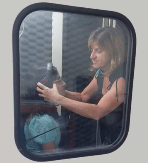 Simone Ebel atendendo criança dentro da cabine audiométrica